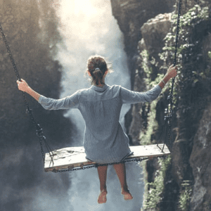 woman on swing overlooking a waterfall