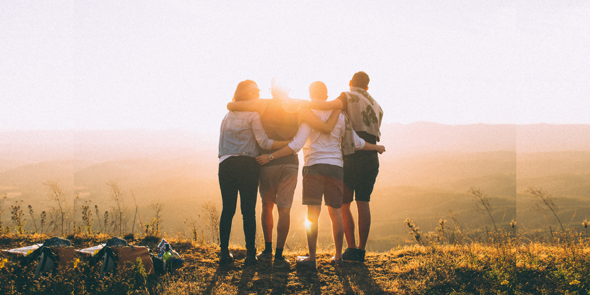 group of four people with their harms around each other at sunset