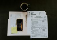 tax documents and a phone calculator on a black tabletop